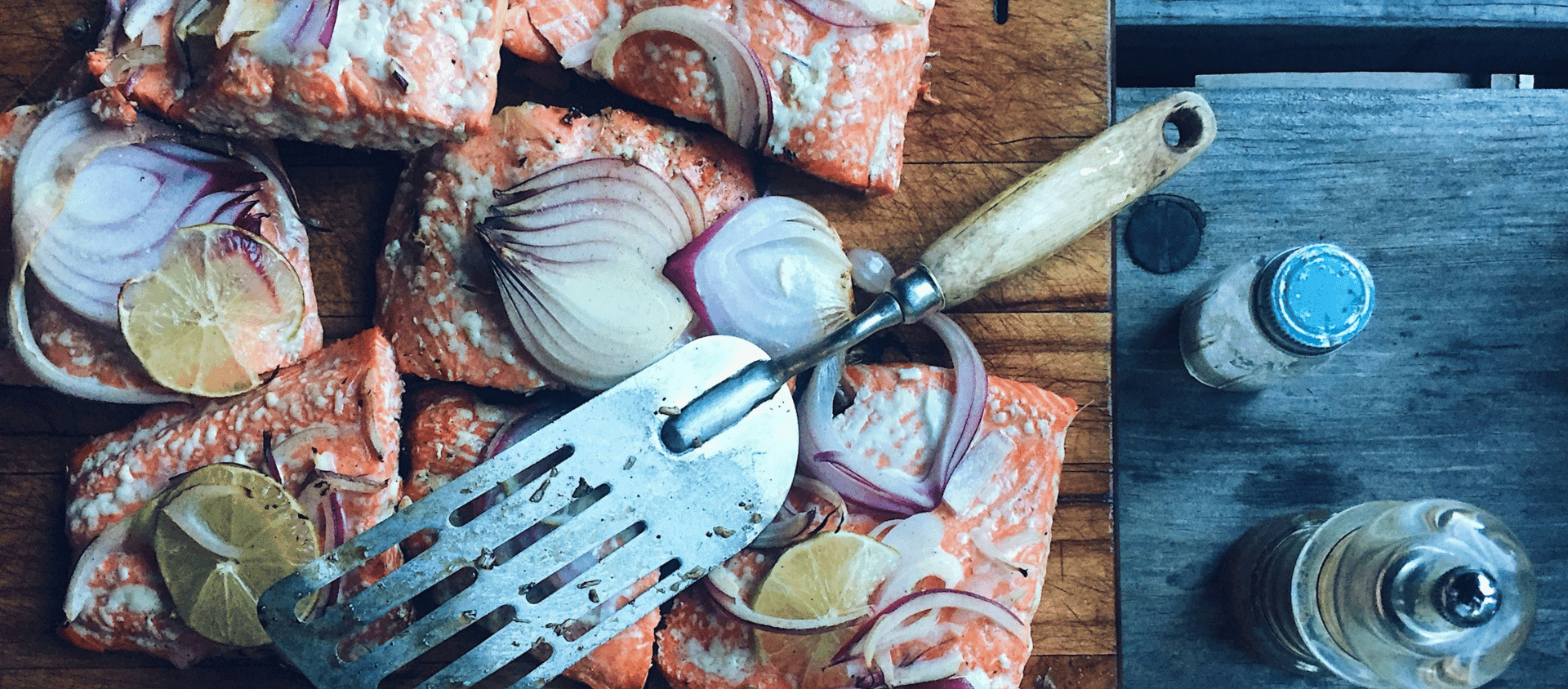 Roasted salmon with vegetables and herbs on a wooden board.