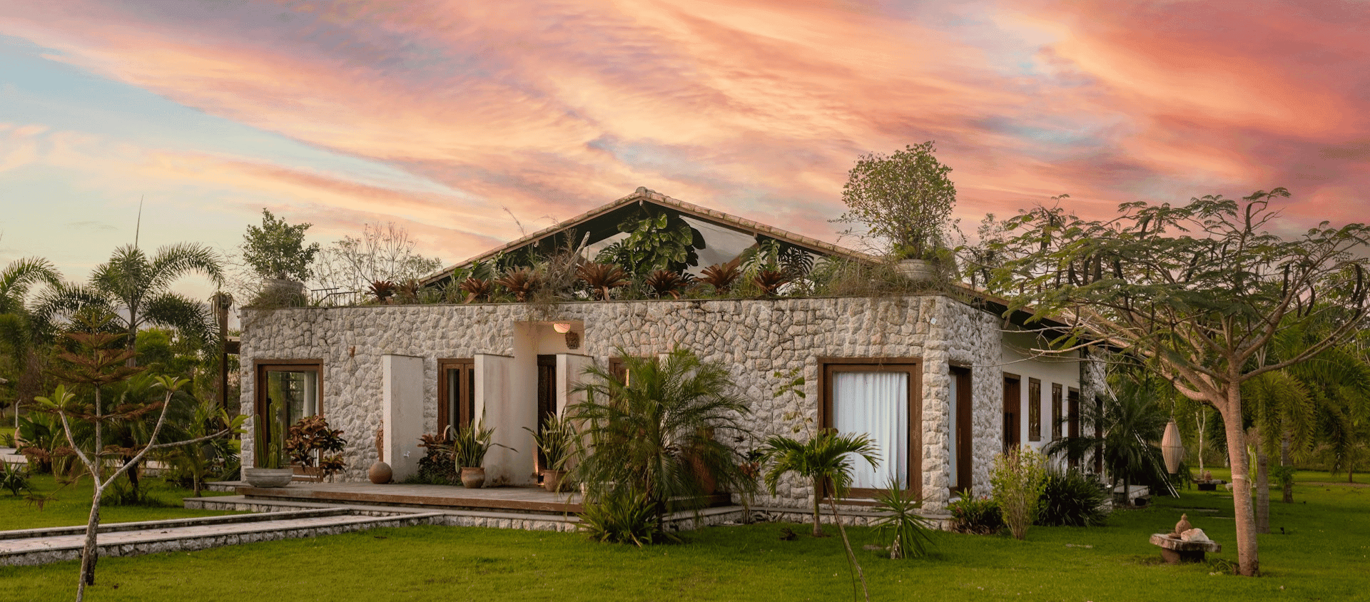 Stone house wedding venue surrounded by greenery at sunset.