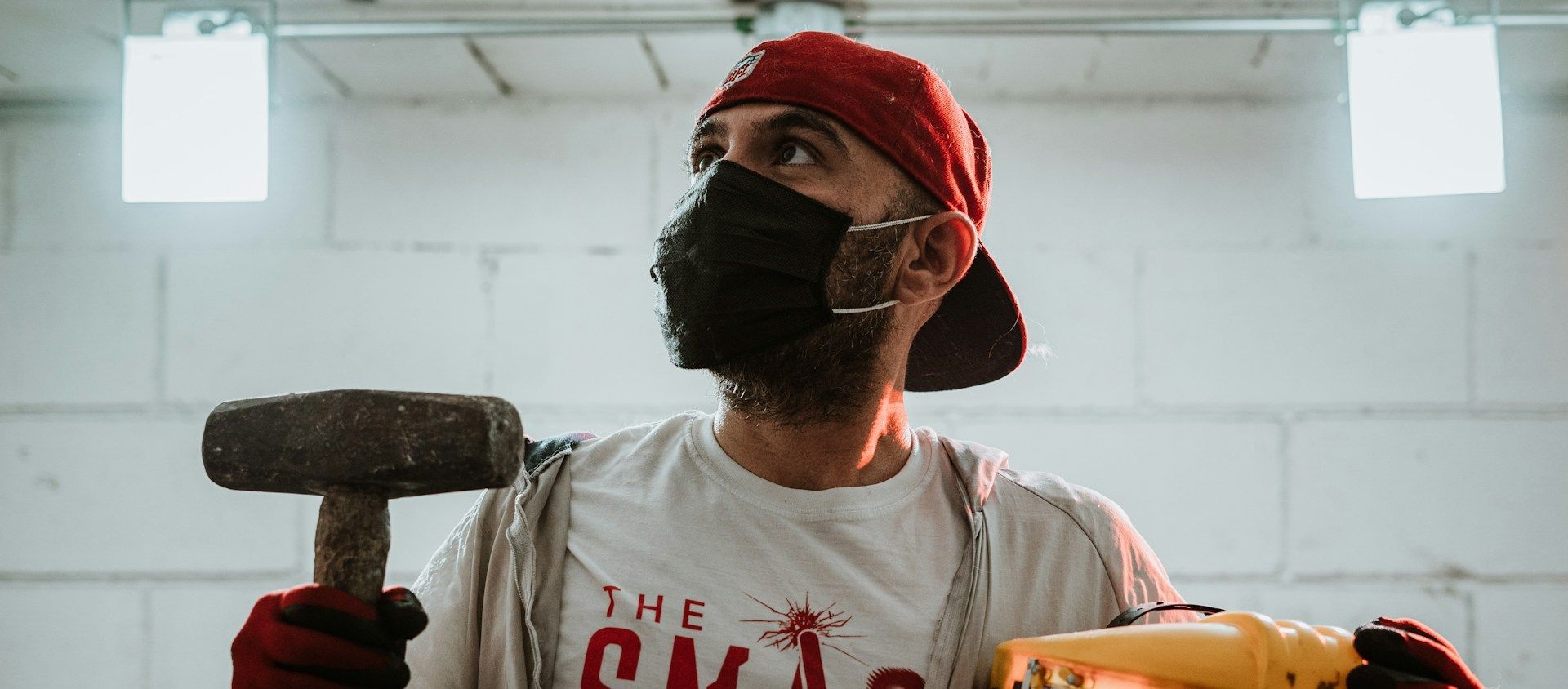 A person in a mask holding a sledgehammer in a rage room.