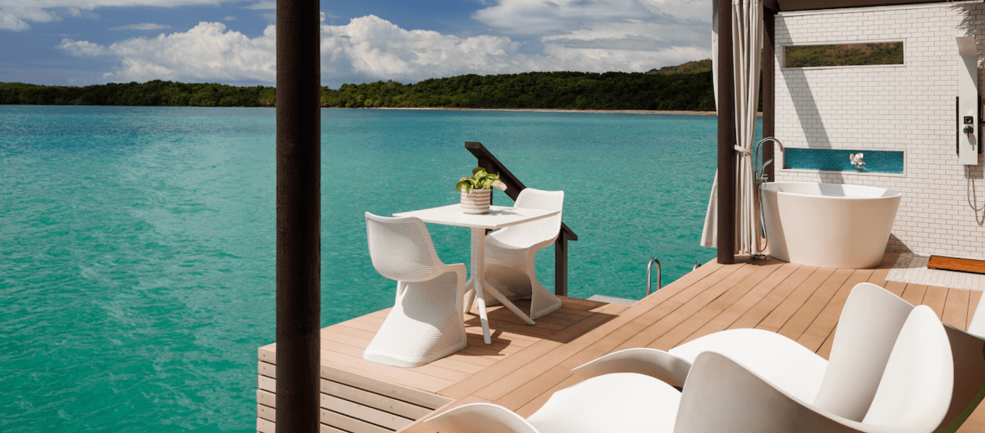white table and chairs on villa balcony over tropical waters