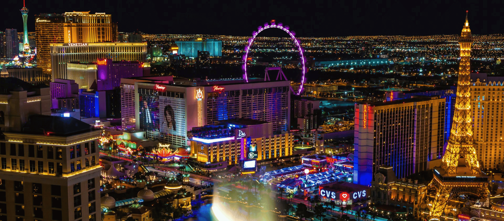 Aerial view of the Las Vegas Strip lit up at night with the High Roller Ferris wheel visible.