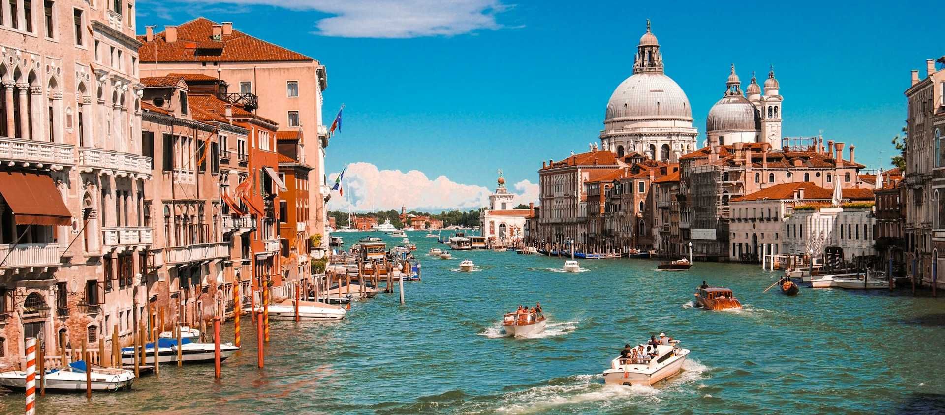Boats cruising the Grand Canal past the domed basilica in Venice, Italy.