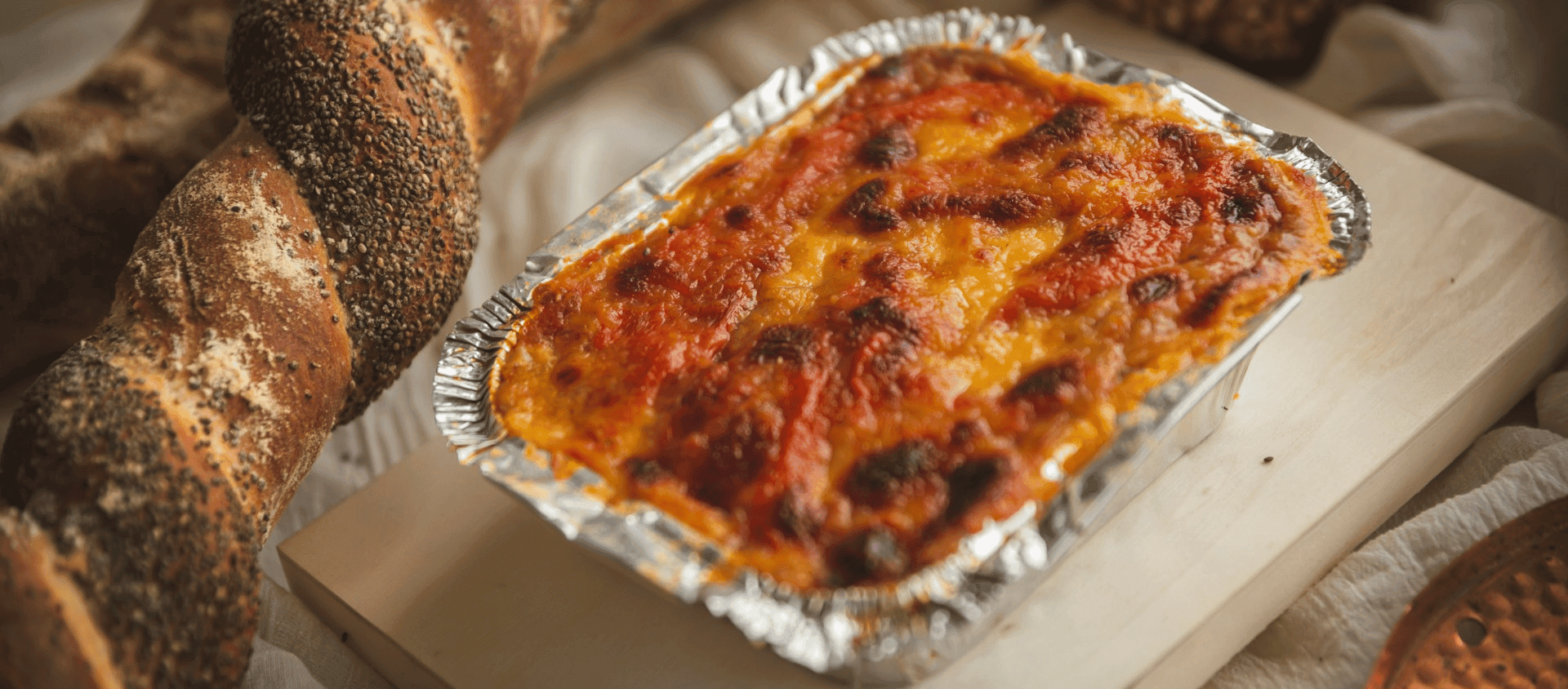 Baked ziti in a casserole dish with melted cheese on top.