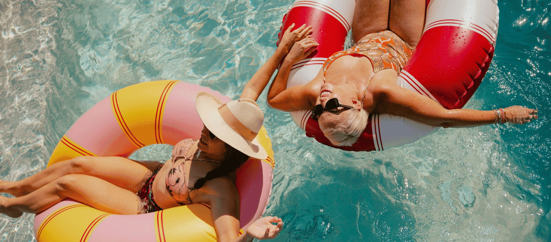 Two women relaxing on inflatable rings in a swimming pool.