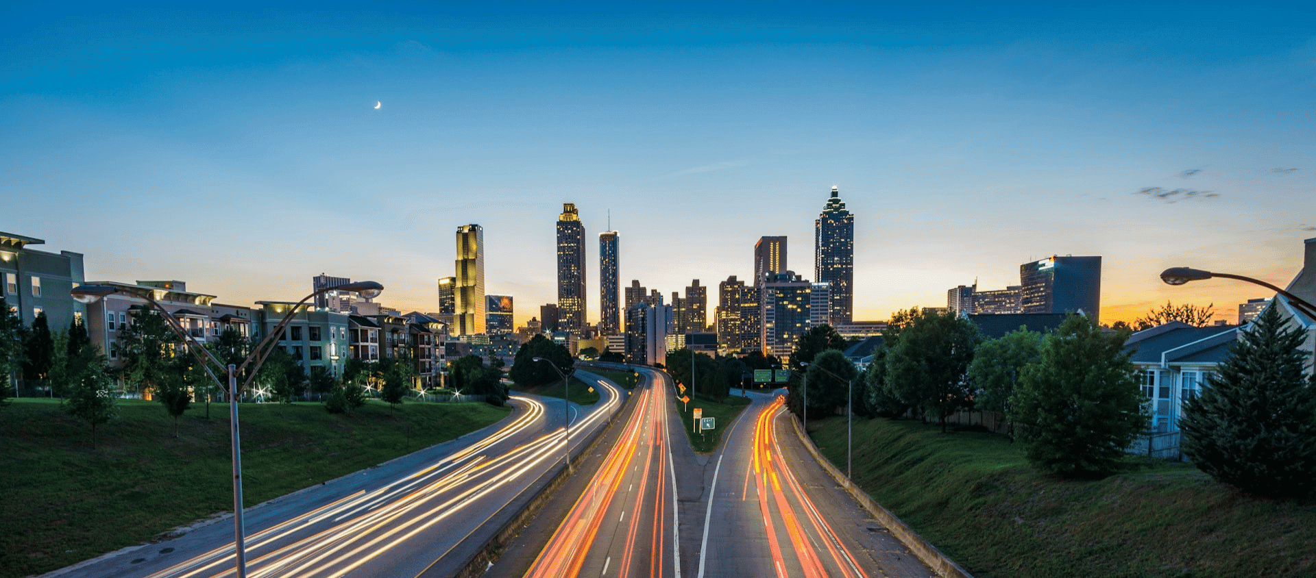 Atlanta skyline at dusk with long-exposure highway light trails in the foreground.