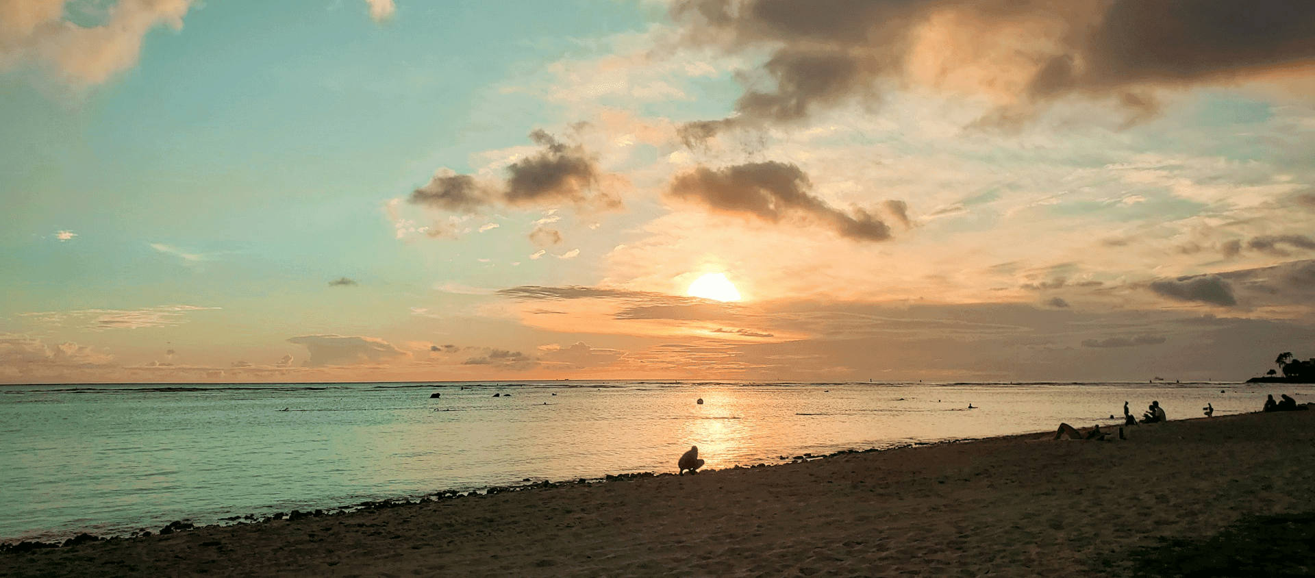 People on Ala Moana beach during the sunset.