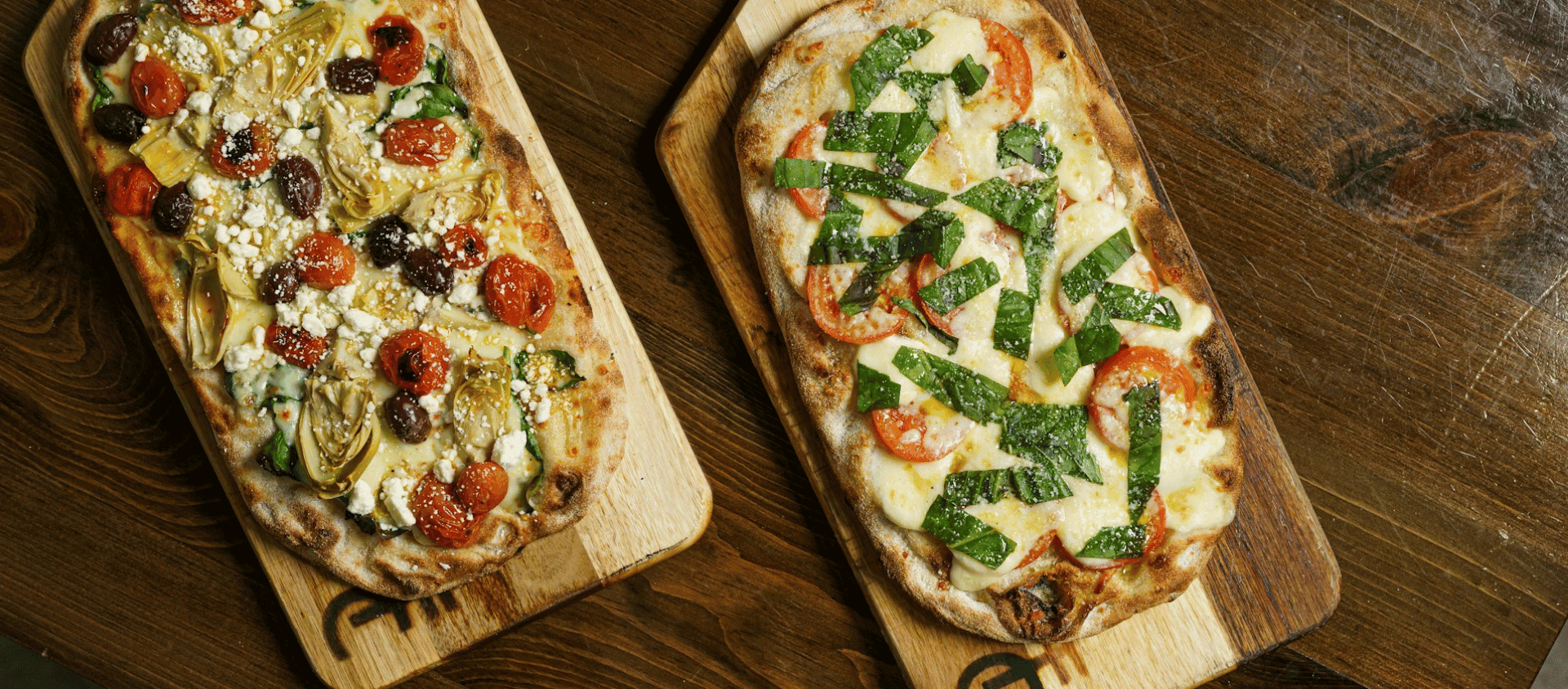 Flatbread pizzas with various toppings on wooden boards.