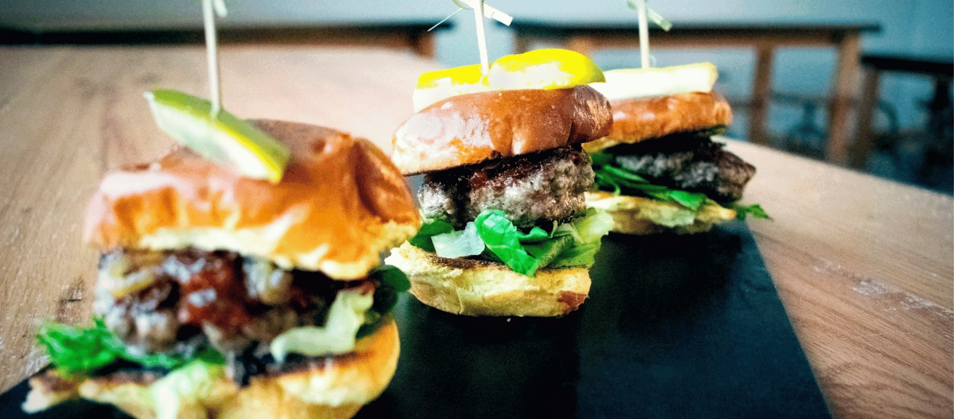 Slider burgers with toppings served on a tray.