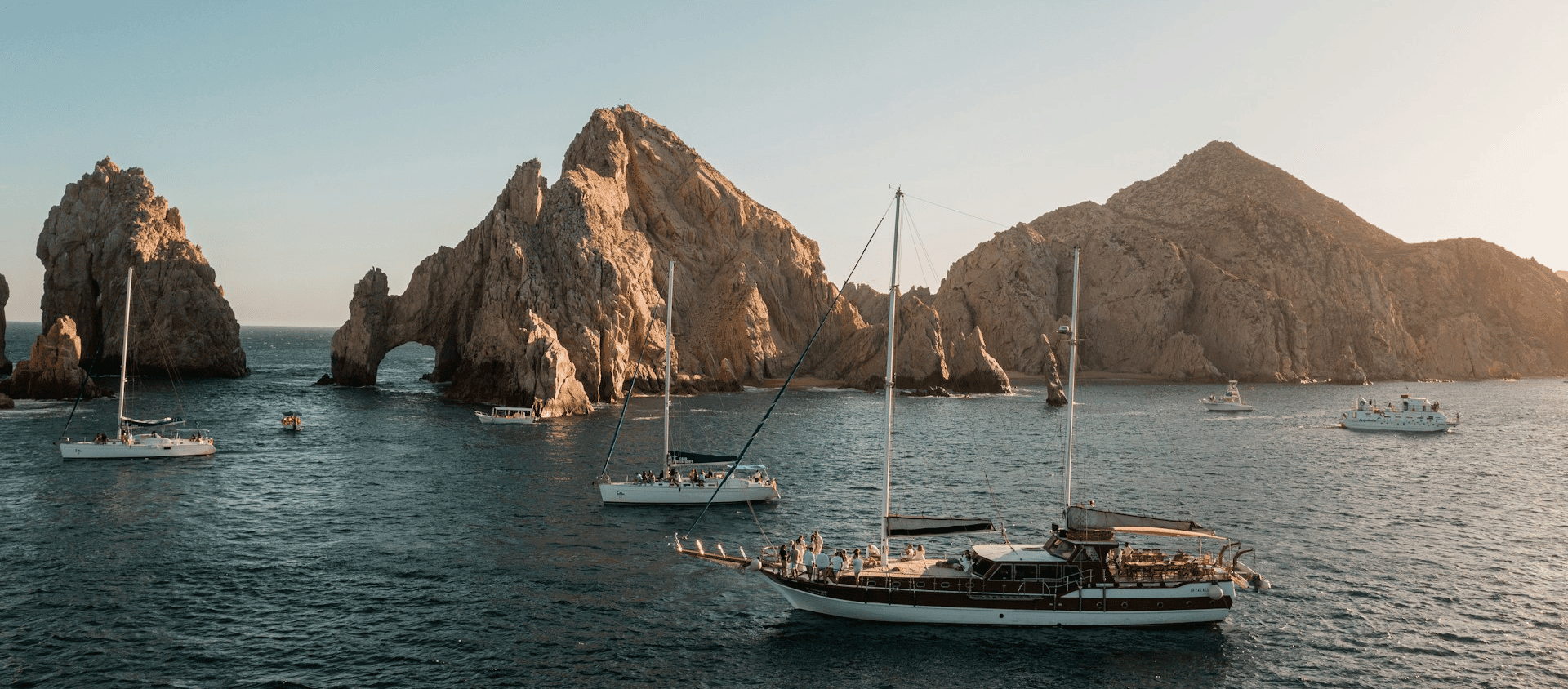 Sailboats anchored near the iconic El Arco rock arch in Cabo San Lucas.