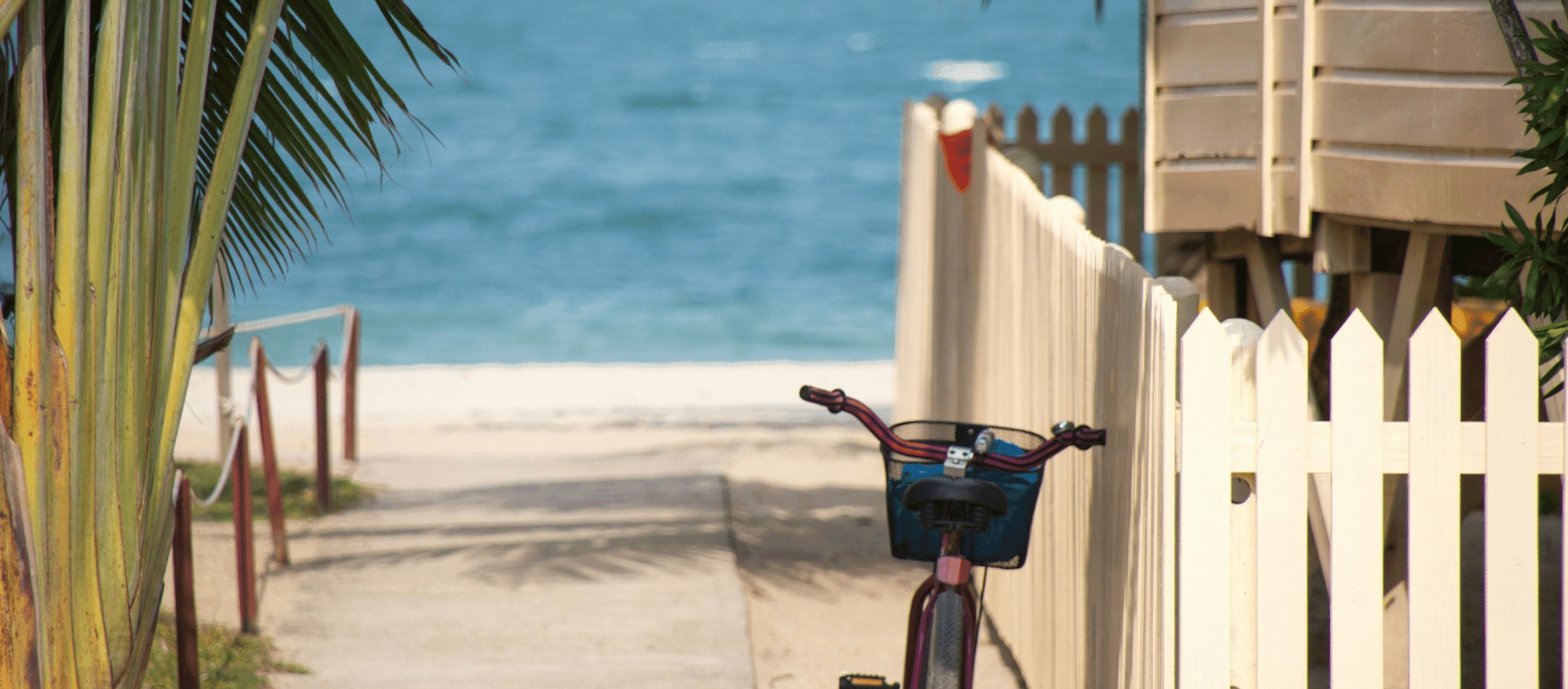 Beachside pathway with white fence and bicycle in Key West.