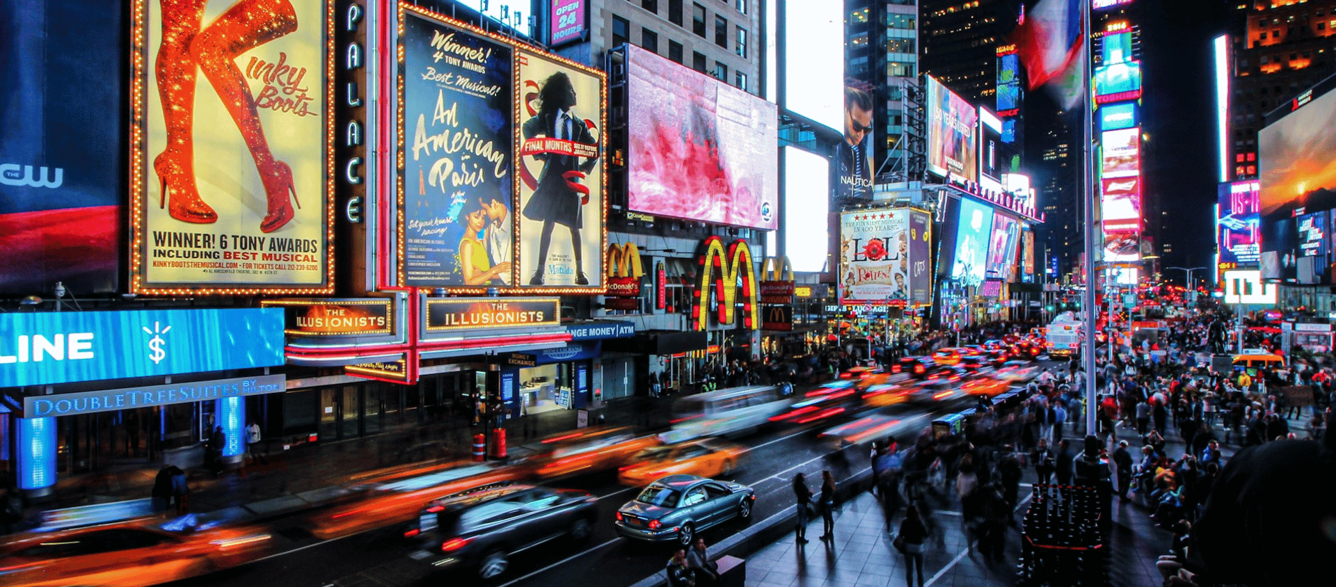 Times Square at night with bright billboards and traffic in Manhattan.