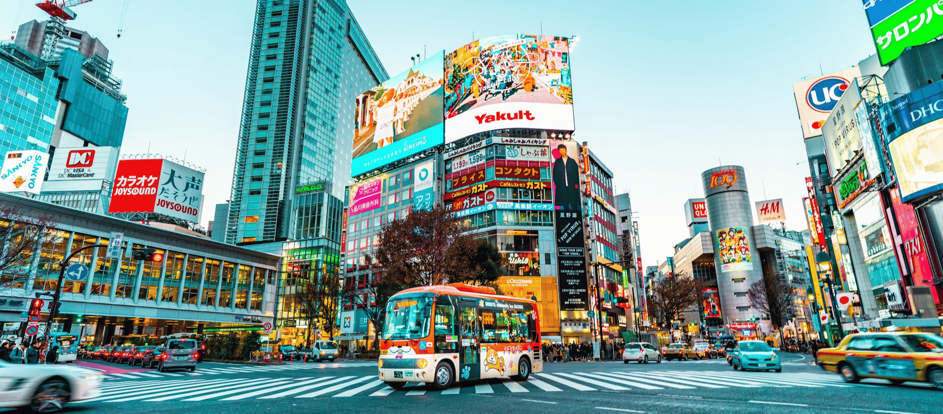 Shibuya Crossing in Tokyo with bright billboards and city traffic.