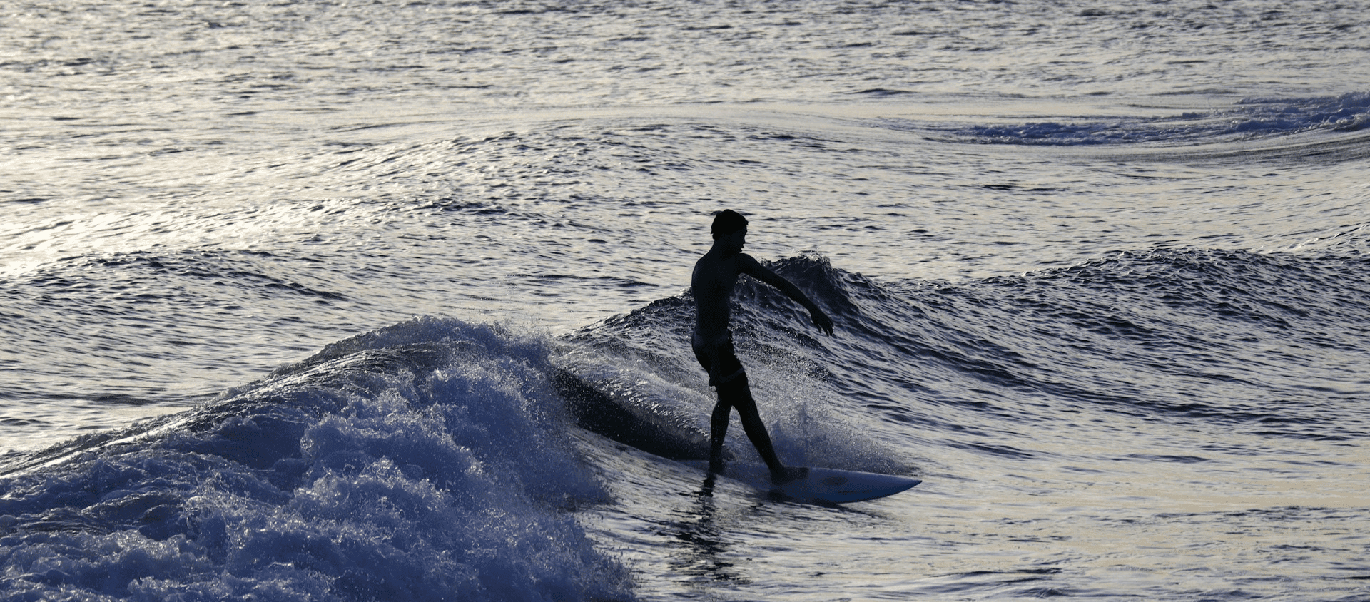 A man in a black wet suit surfing during the daytime in Hawaii
