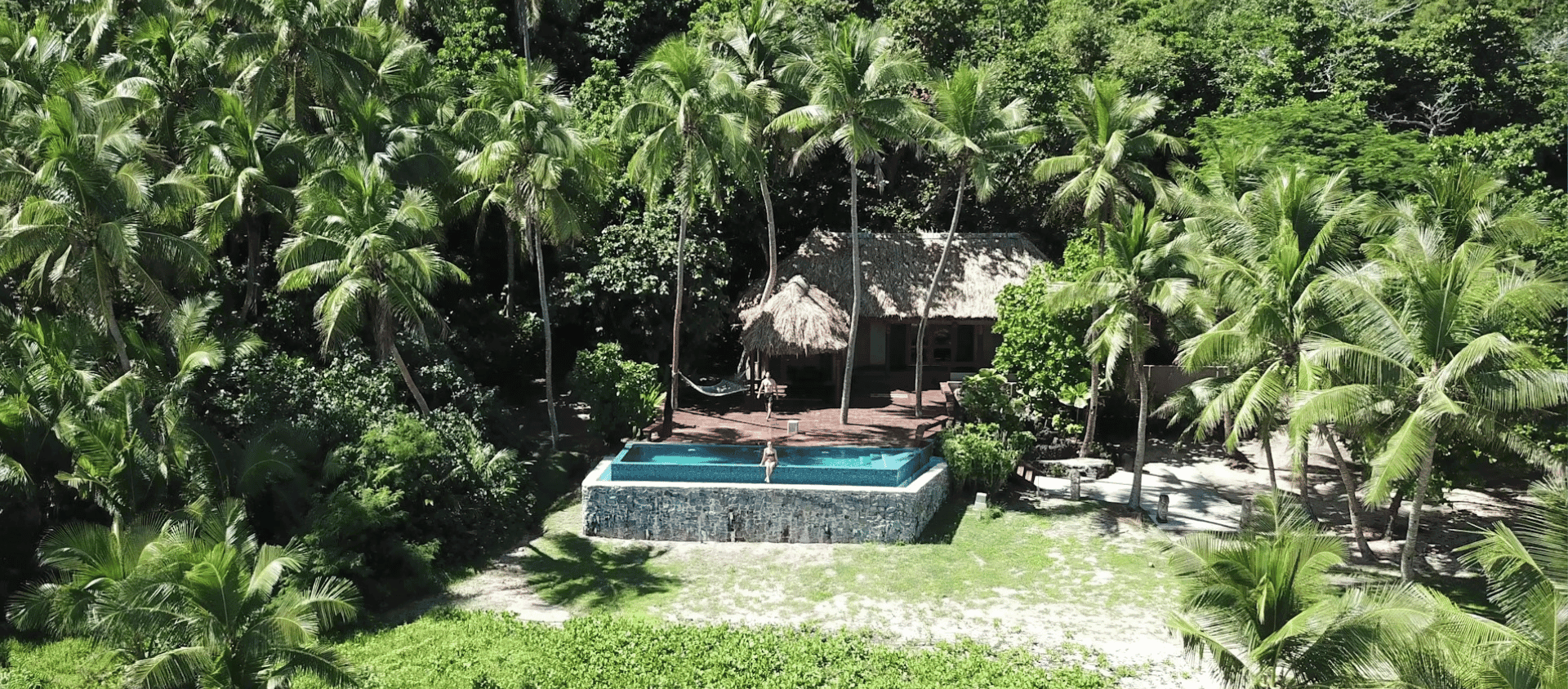 Secluded island resort villa nestled in dense palm forest with a private infinity pool.
