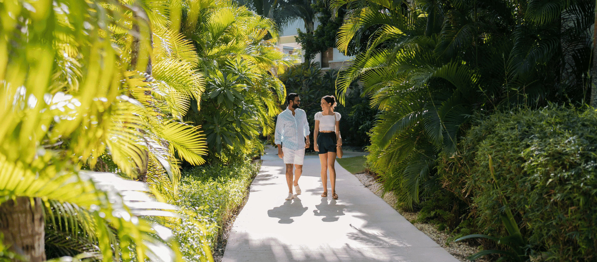 Couple walking hand in hand through lush tropical gardens at Secrets Cap Cana.