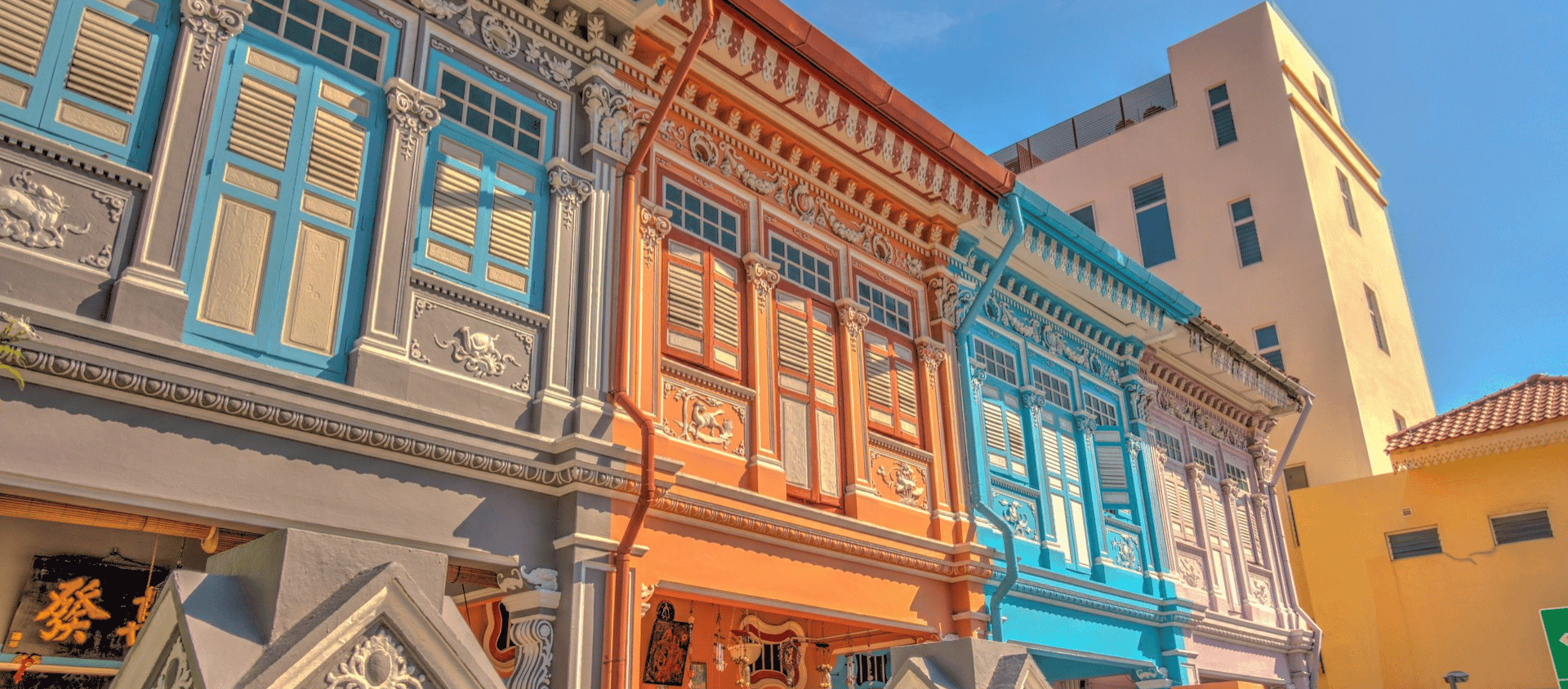 Row of brightly painted heritage Peranakan shophouses with blue shuttered windows in Singapore