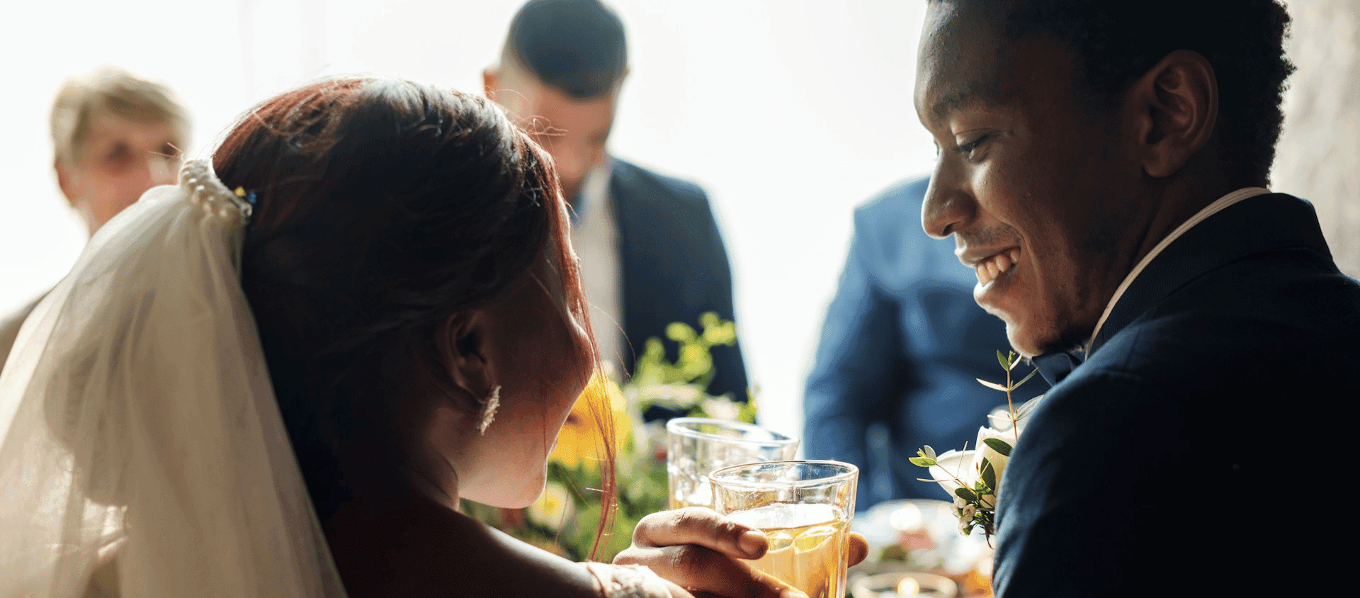 Newlyweds smiling and toasting with drinks during the reception.