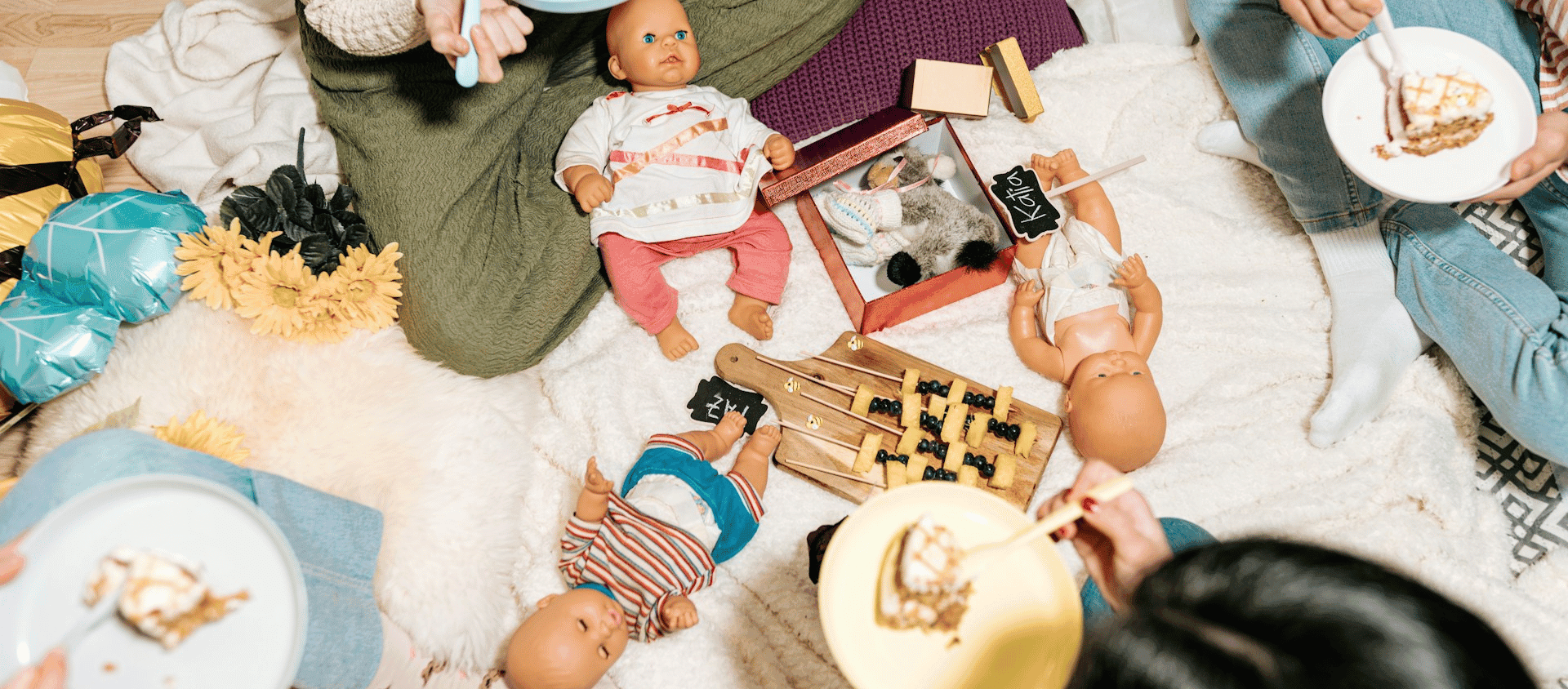 Baby dolls and games arranged on the floor during a baby shower gathering.
