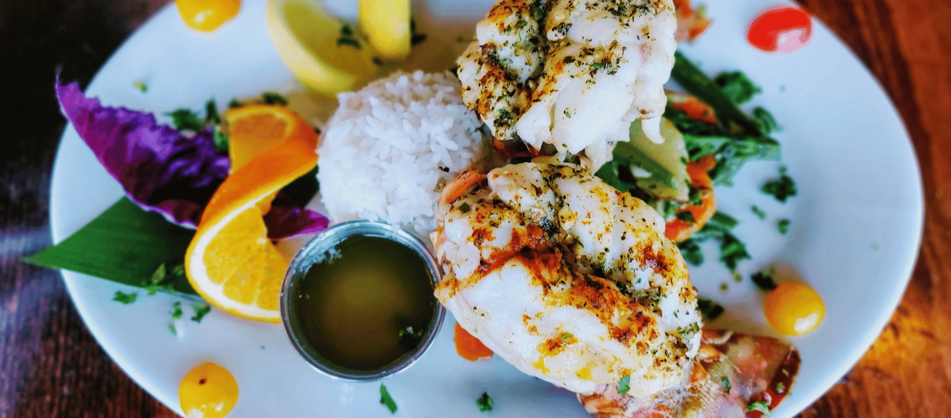 Garlic butter lobster tails topped with seasoning and rice on the side.