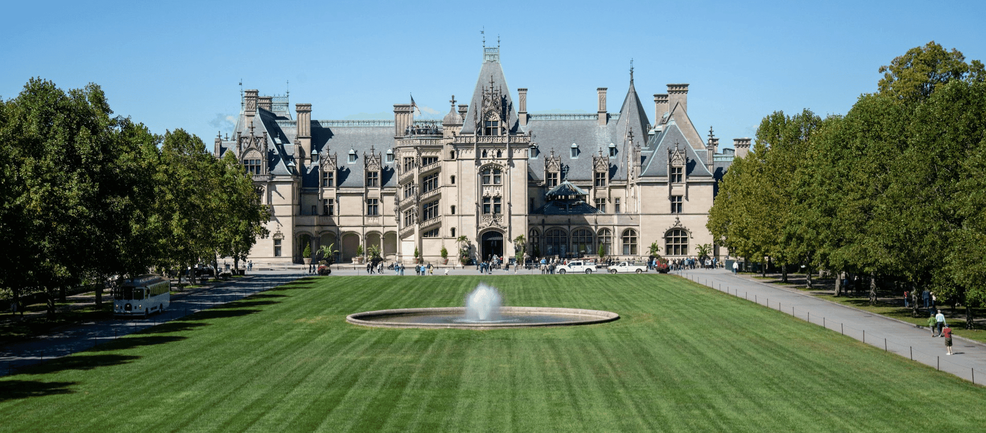 Grand facade of the Biltmore Estate with a fountain and manicured lawns in Asheville.