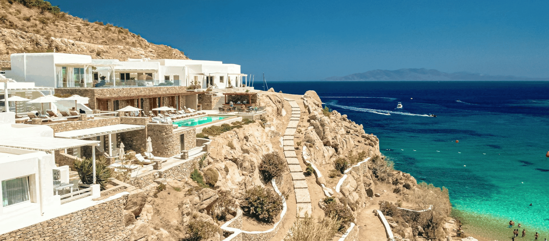 Luxury seaside villa on rocky cliffs above turquoise Mediterranean water.