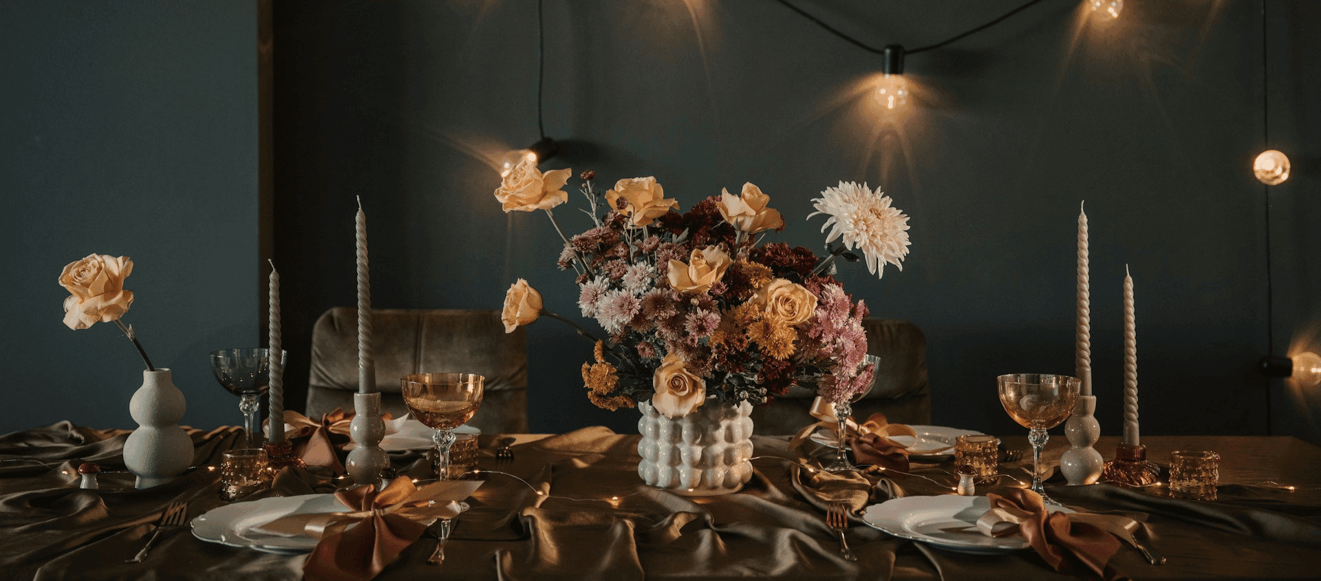 Moody, candlelit table setting with floral centerpiece and gold accents.