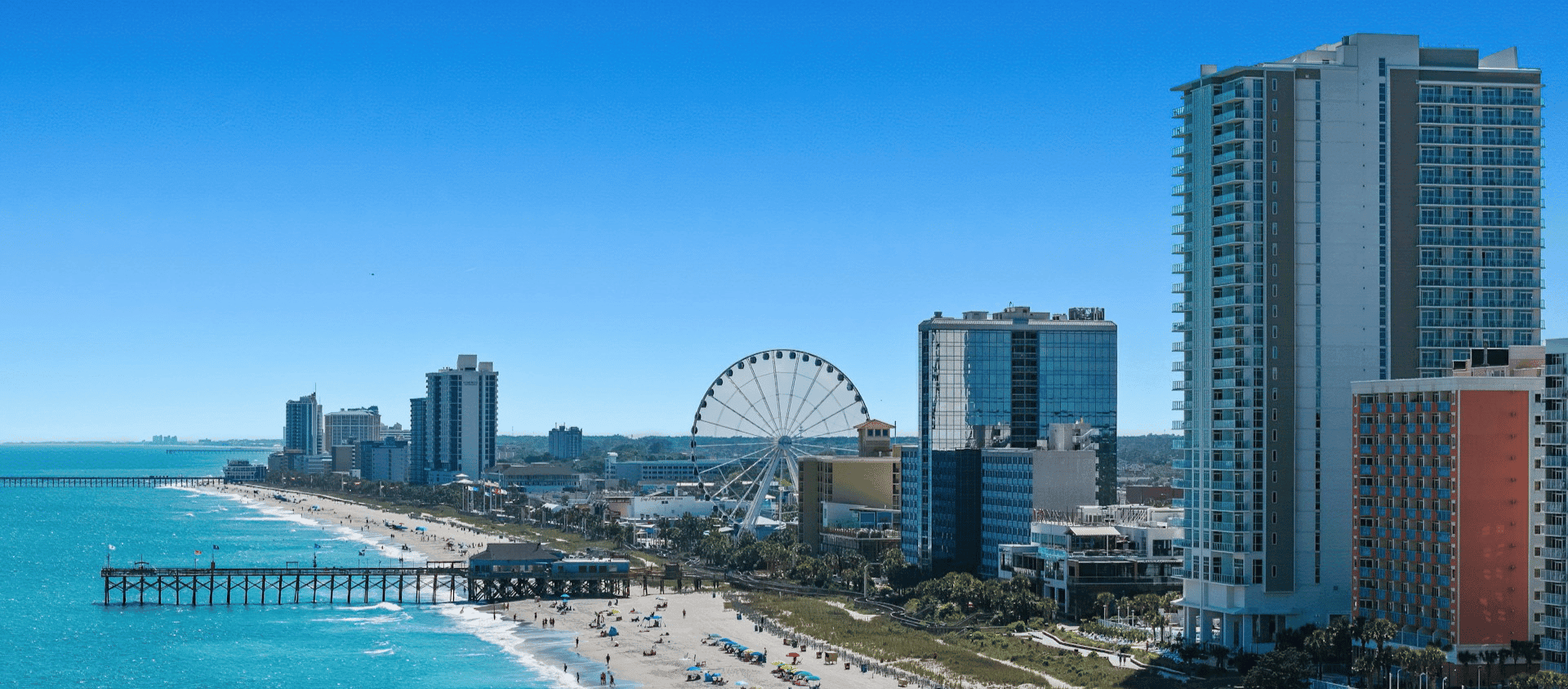 Oceanfront city skyline with beach, pier, and Ferris wheel along the South Carolina coast.