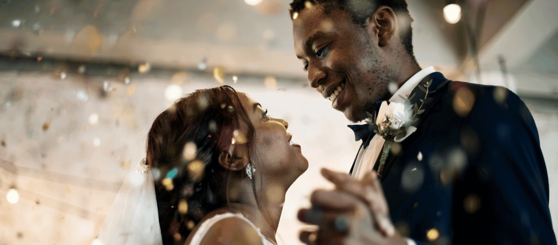 The newly married couple dancing together under falling confetti.