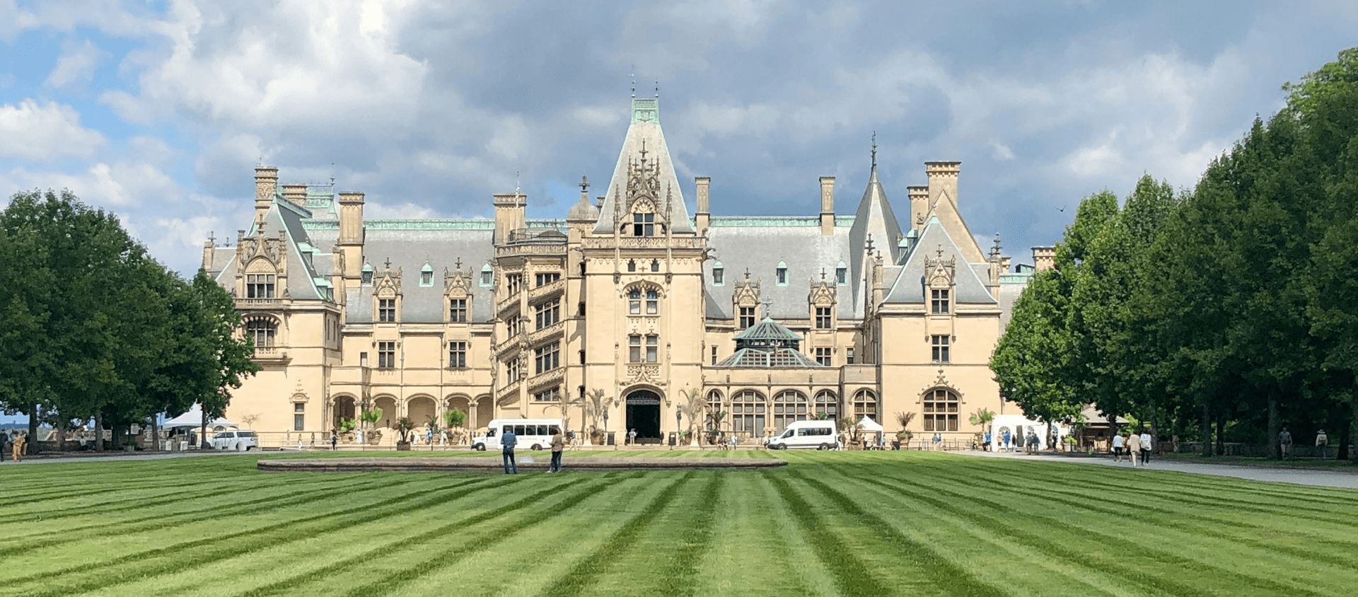 green lawn leading up to large tan colored castle lined by trees