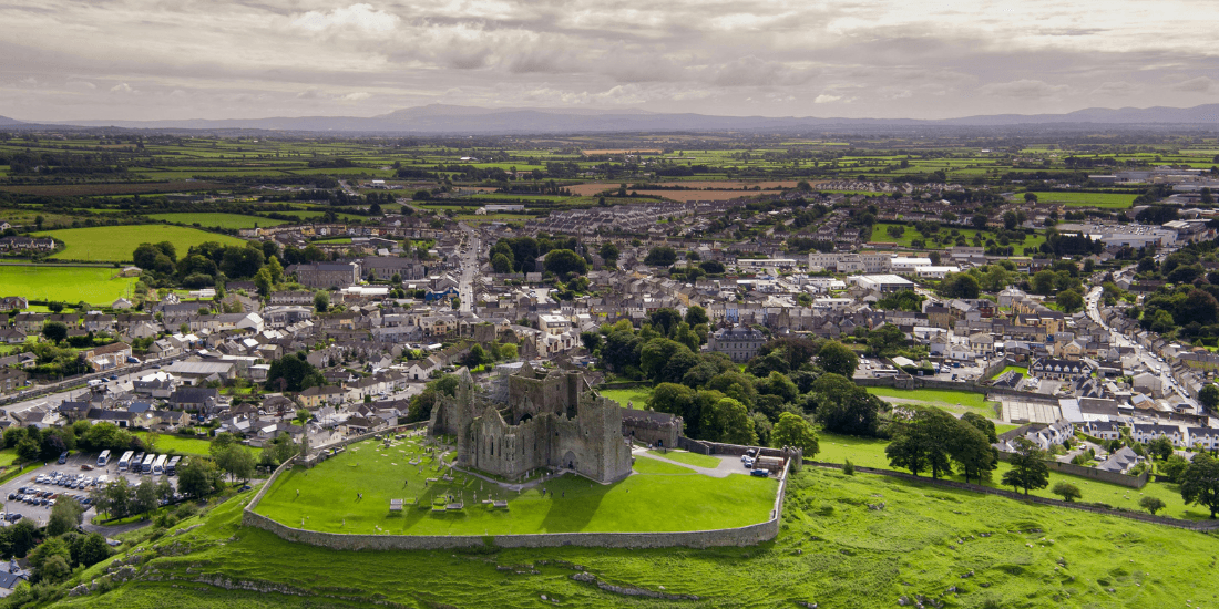 Aerial view of castle ruins on a hill above a small Irish town.