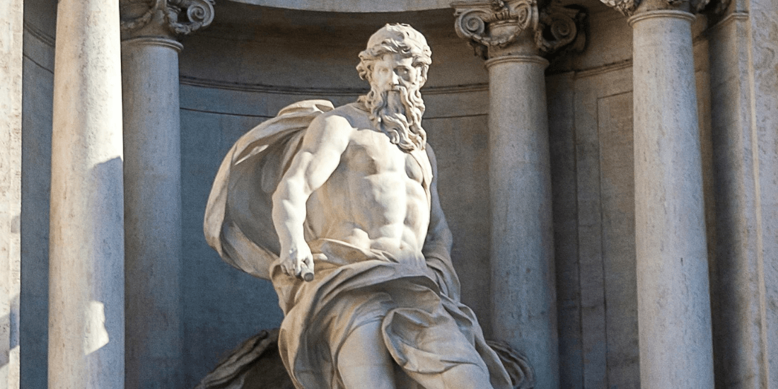 Classical marble statue of a bearded man seated among stone columns.