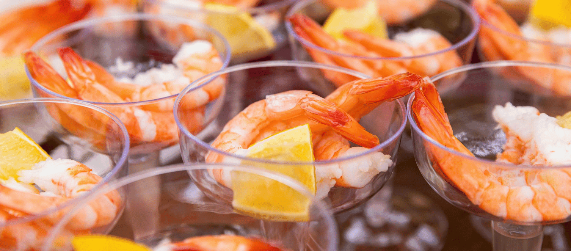 Shrimp cocktail served in glasses with lemon wedges and dipping sauce.