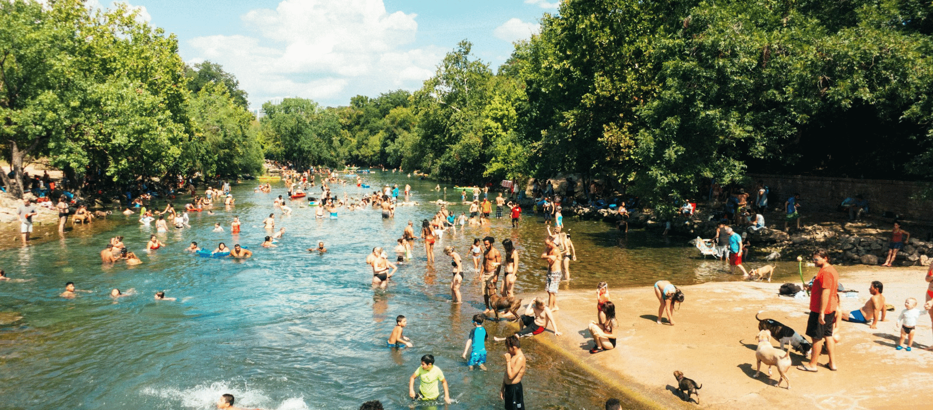 Crowd of people swimming and relaxing at Barton Springs Pool in Austin.