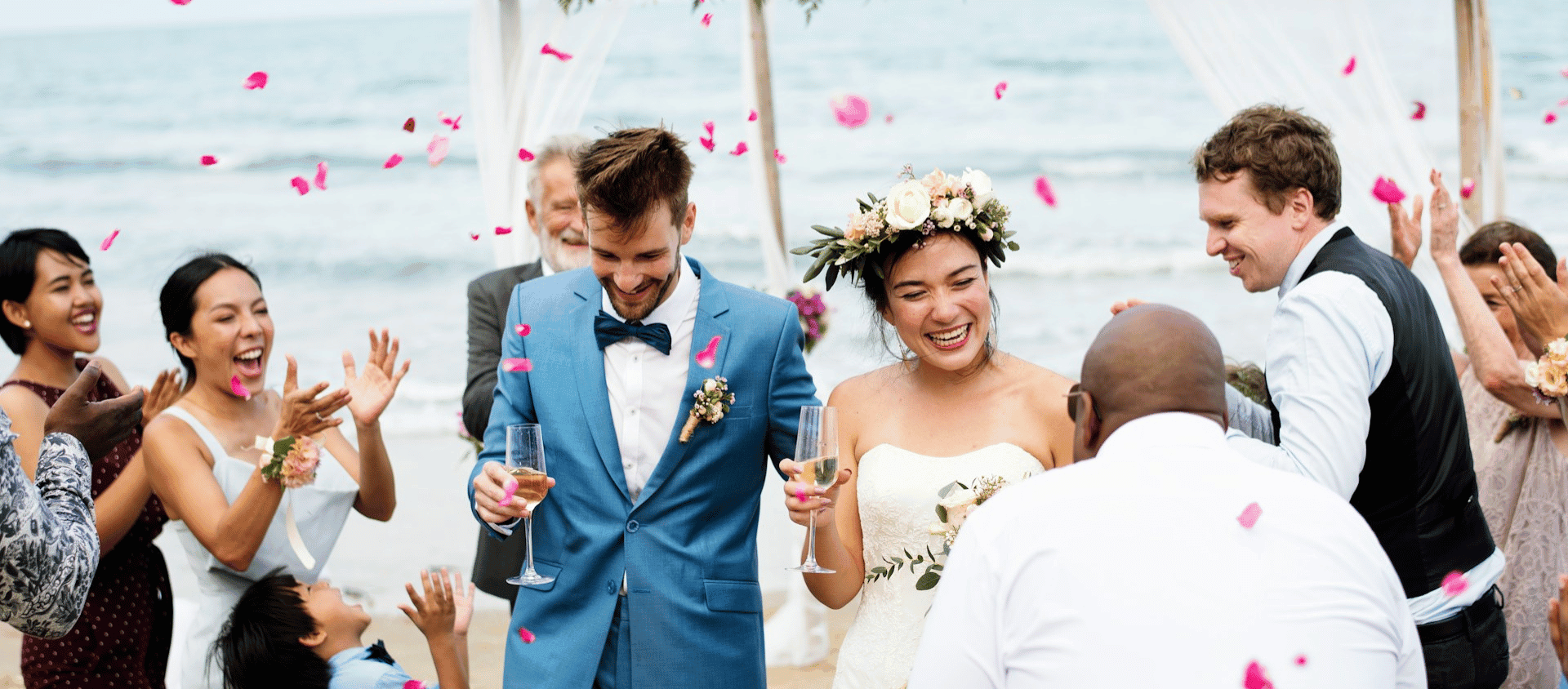 Bride and groom celebrating with guests at a beach wedding.