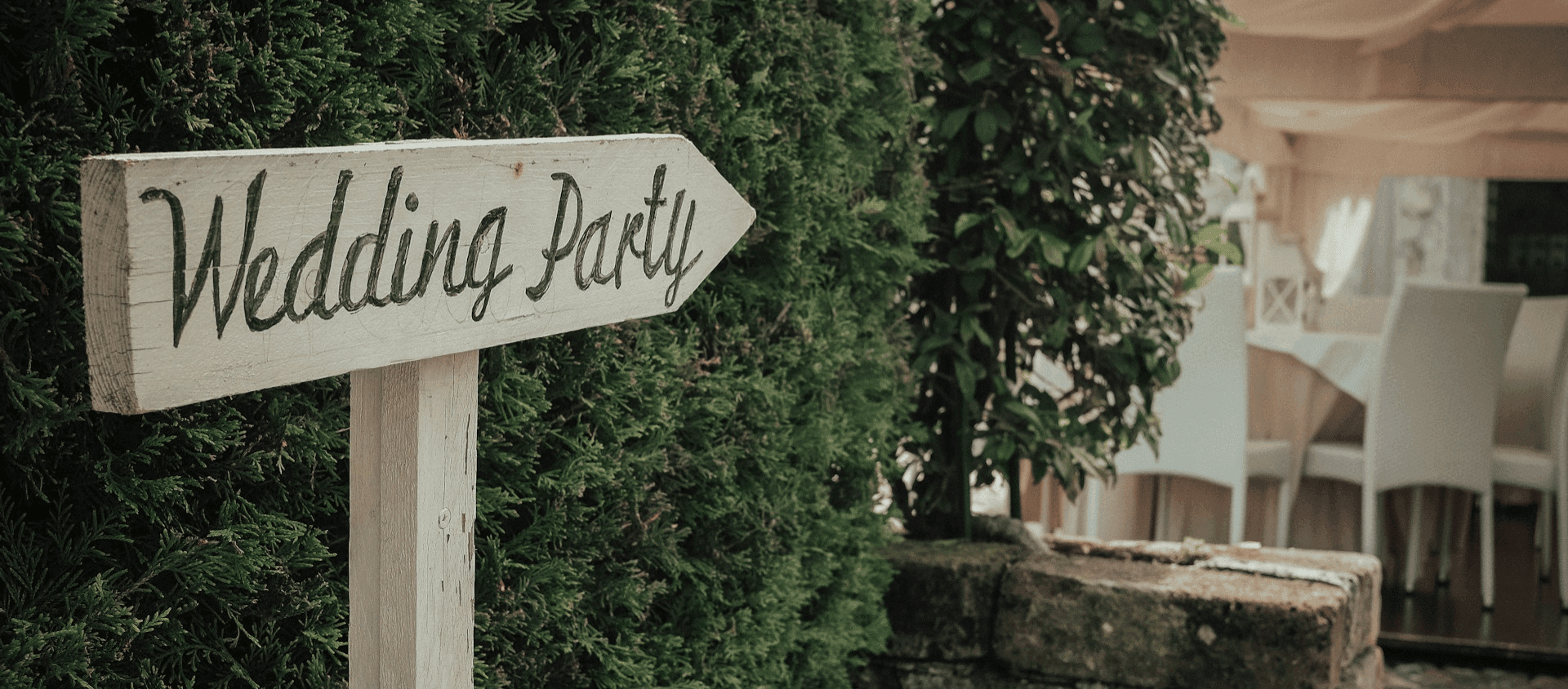 Wooden sign reading “Wedding Party” pointing toward an outdoor venue.