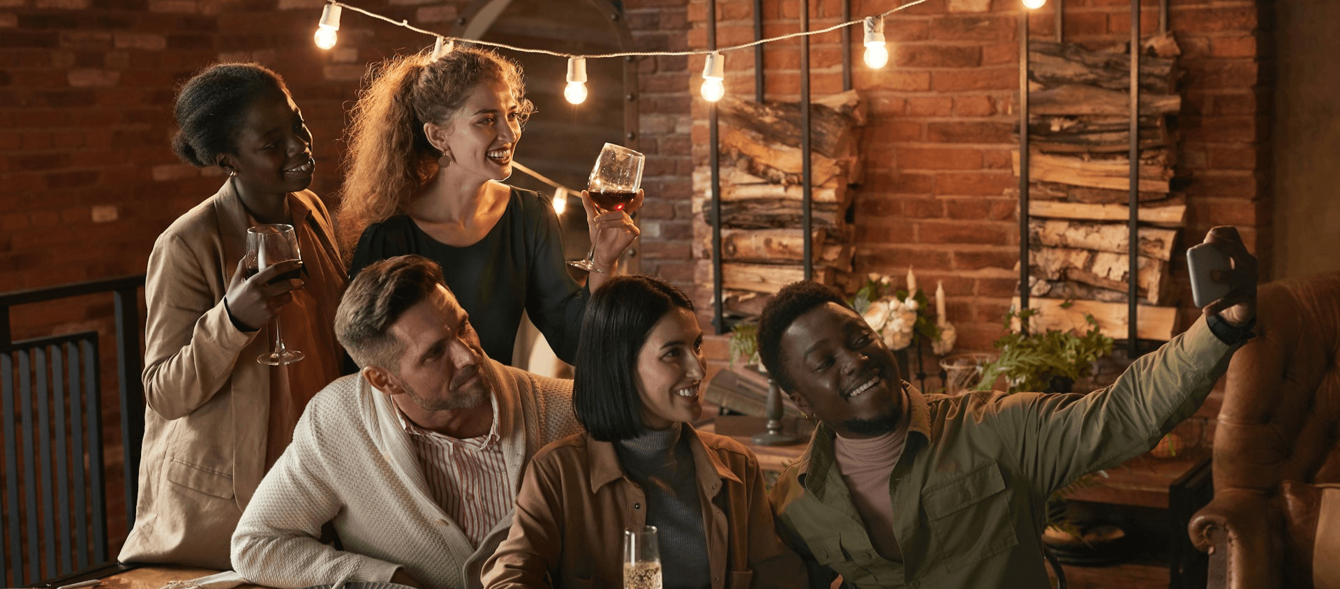 Froup of friends taking a selfie and enjoying drinks in a cozy cabin.