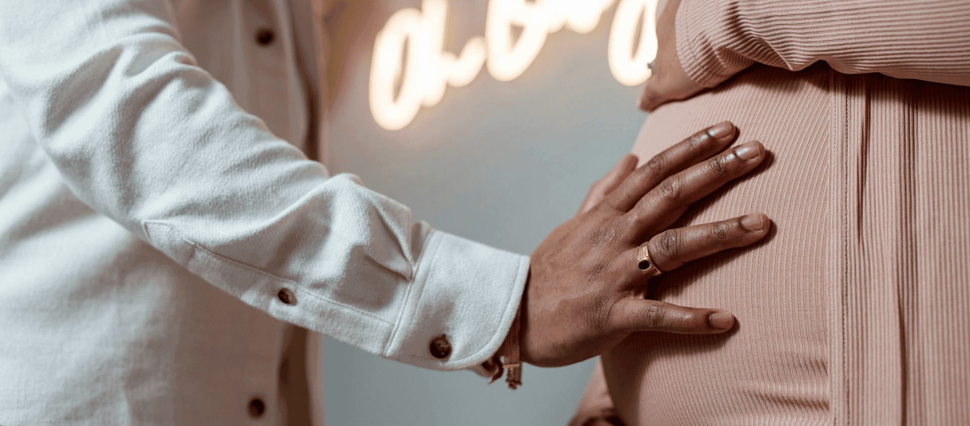 A person gently placing a hand on a pregnant woman’s belly.
