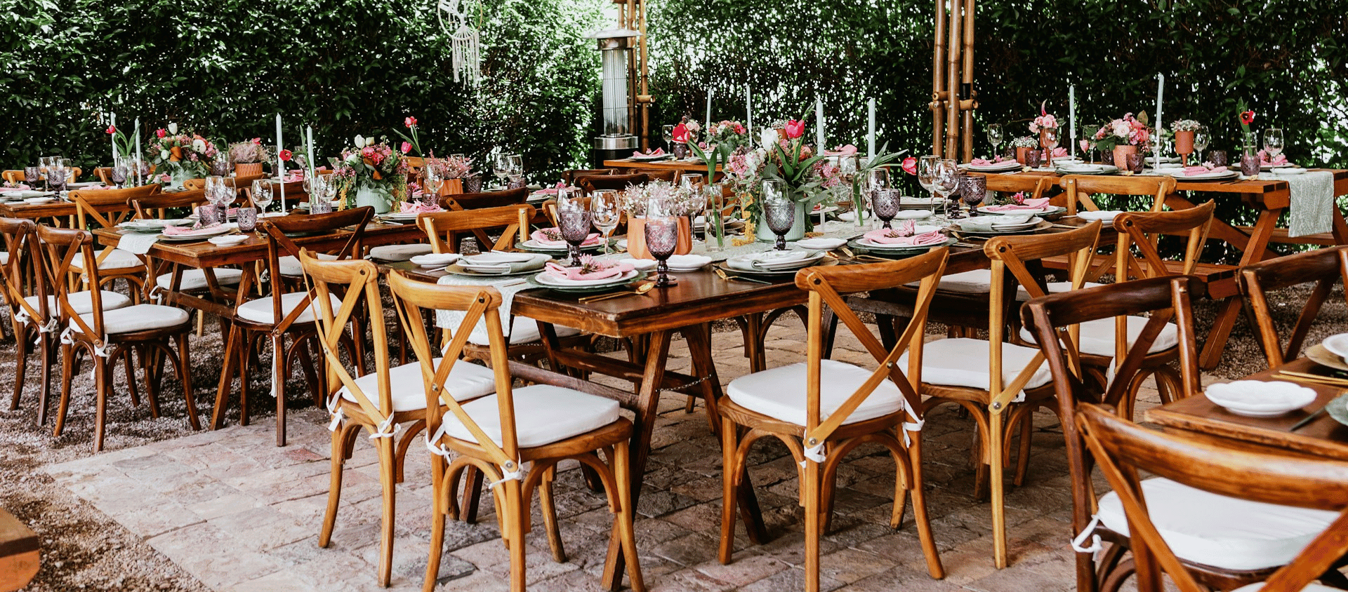Outdoor dining setup with long tables and floral arrangements.
