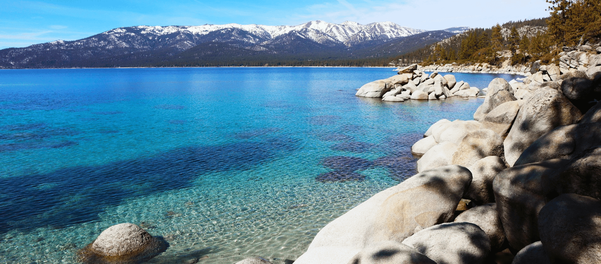 Crystal clear blue water and granite boulders along the Lake Tahoe shoreline.
