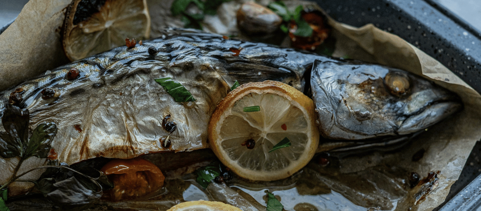 Whole roasted fish garnished with lemon slices.