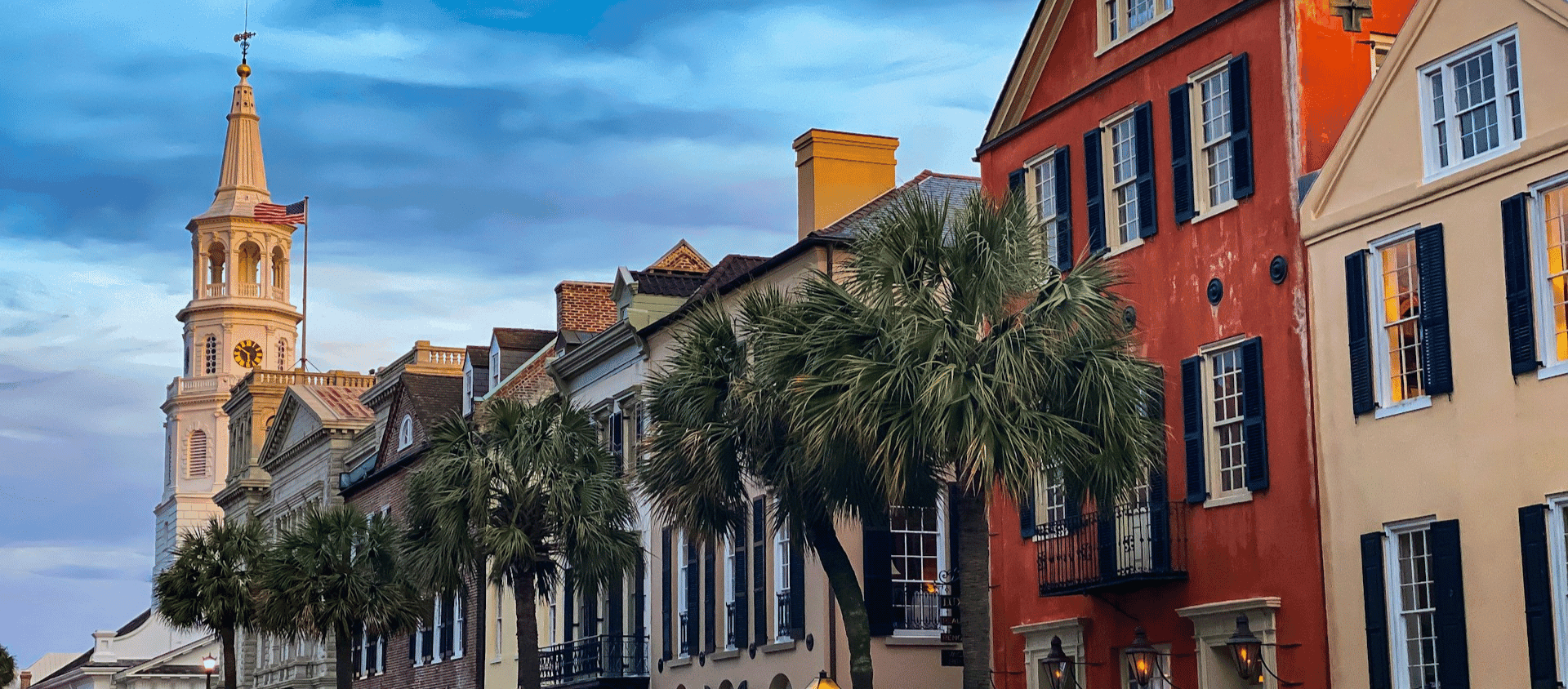 Historic homes and palm lined street in Charleston’s French Quarter with St. Michael’s Church in the background.