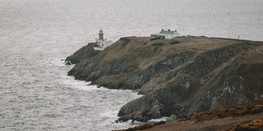 Lighthouse on rugged green sea cliffs along the Irish coast.