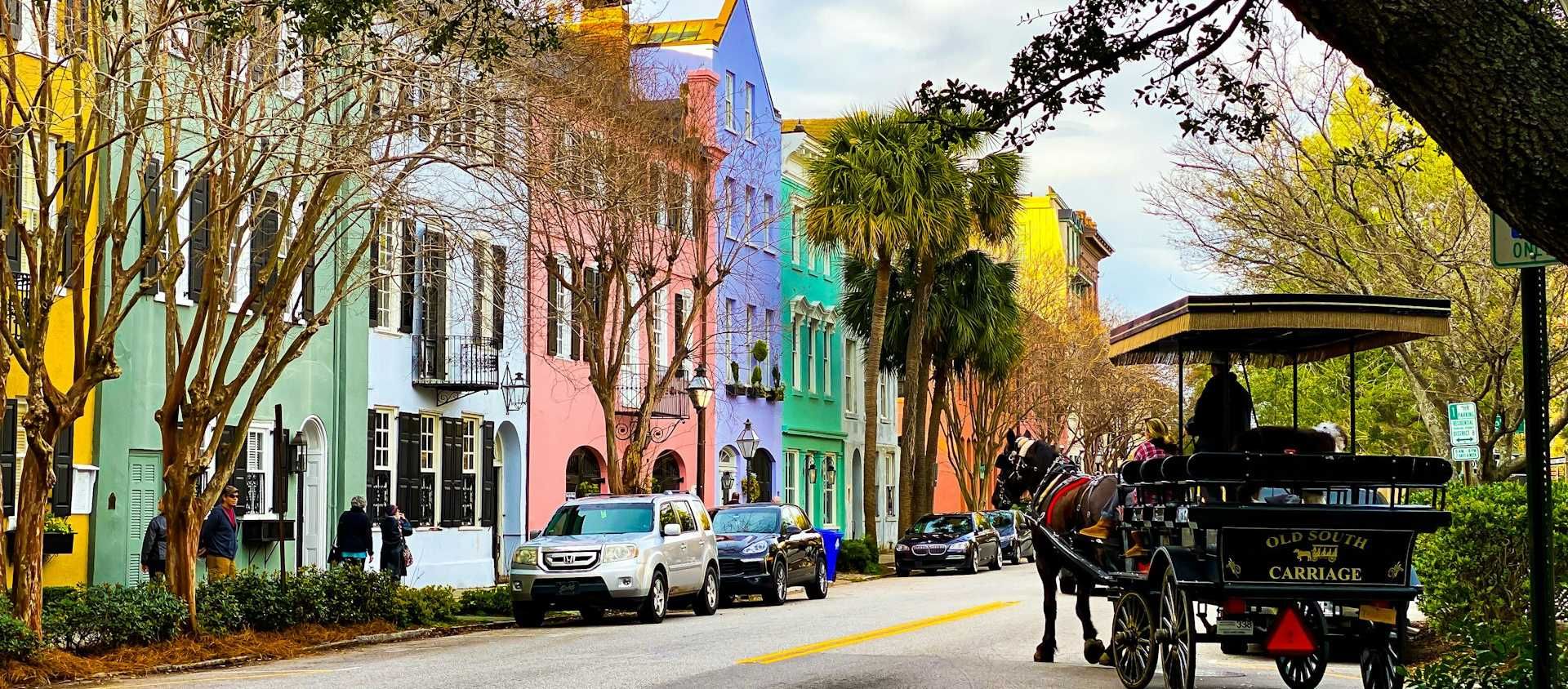 A horse-drawn carriage passing the pastel homes of Rainbow Row in Charleston.