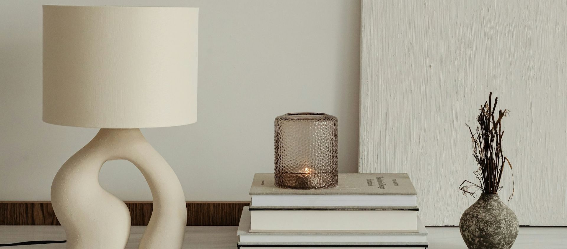 A ceramic lamp, candle holder, and small vase styled as home decor.