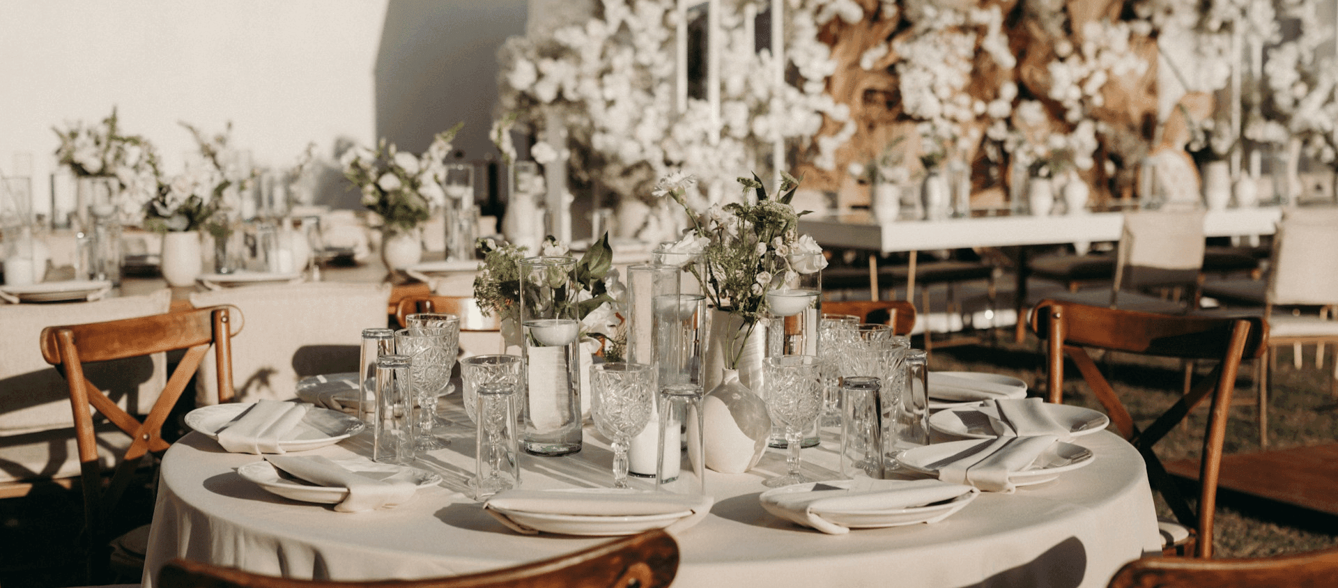 Elegantly set wedding reception table with glassware and floral centerpieces.