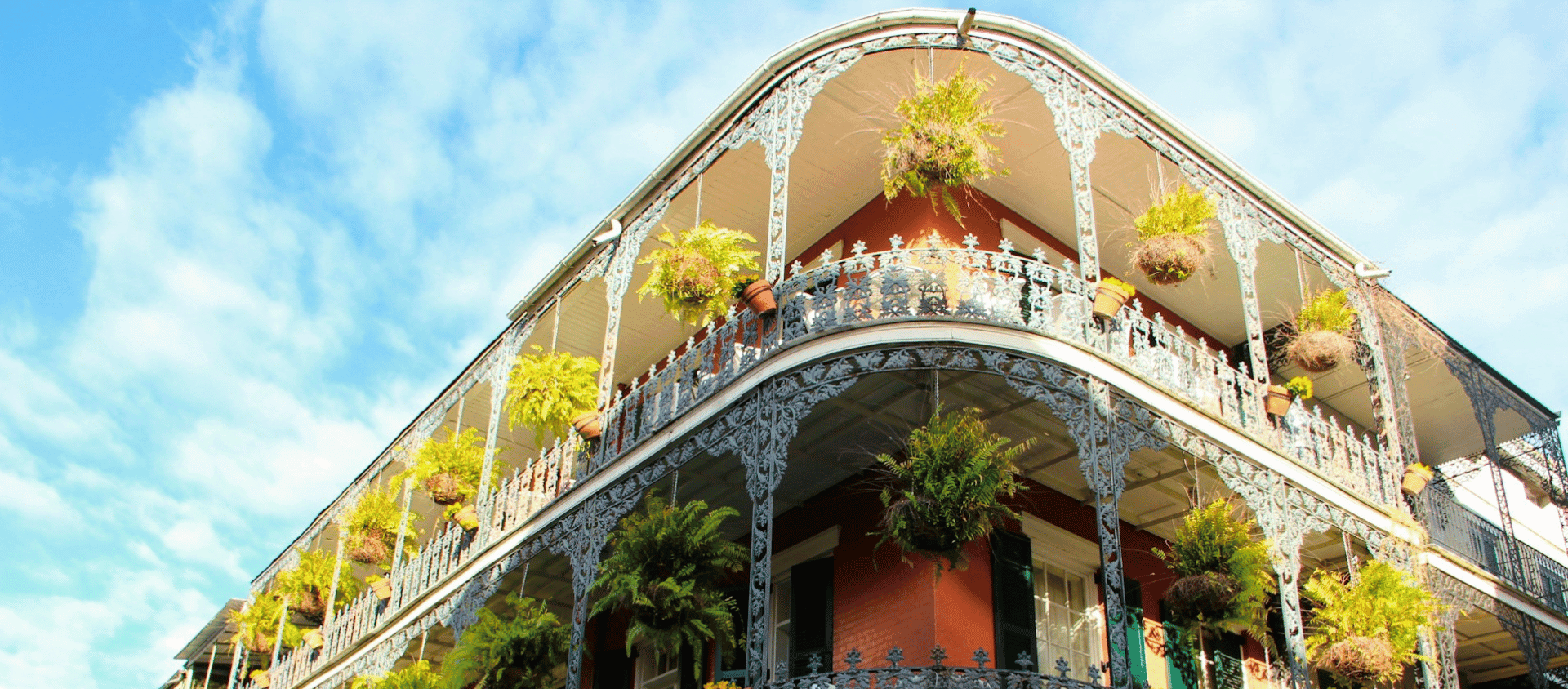 Historic French Quarter building with ornate iron balconies and hanging plants in New Orleans.
