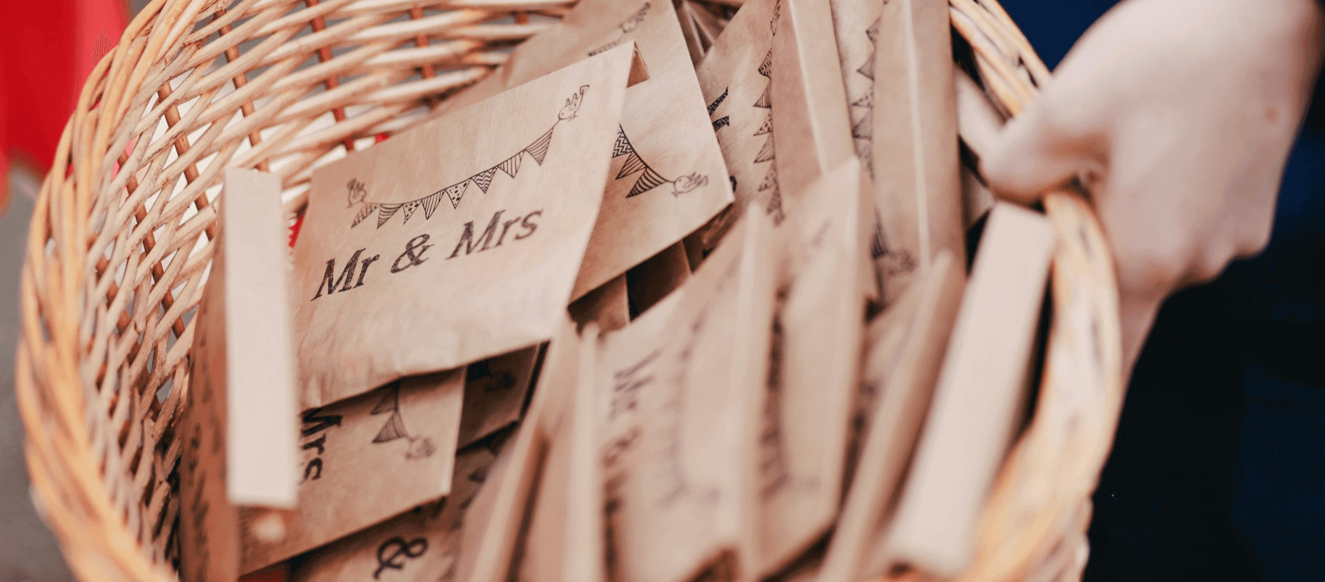 Wicker basket holding paper wedding favors labeled ‘Mr & Mrs.