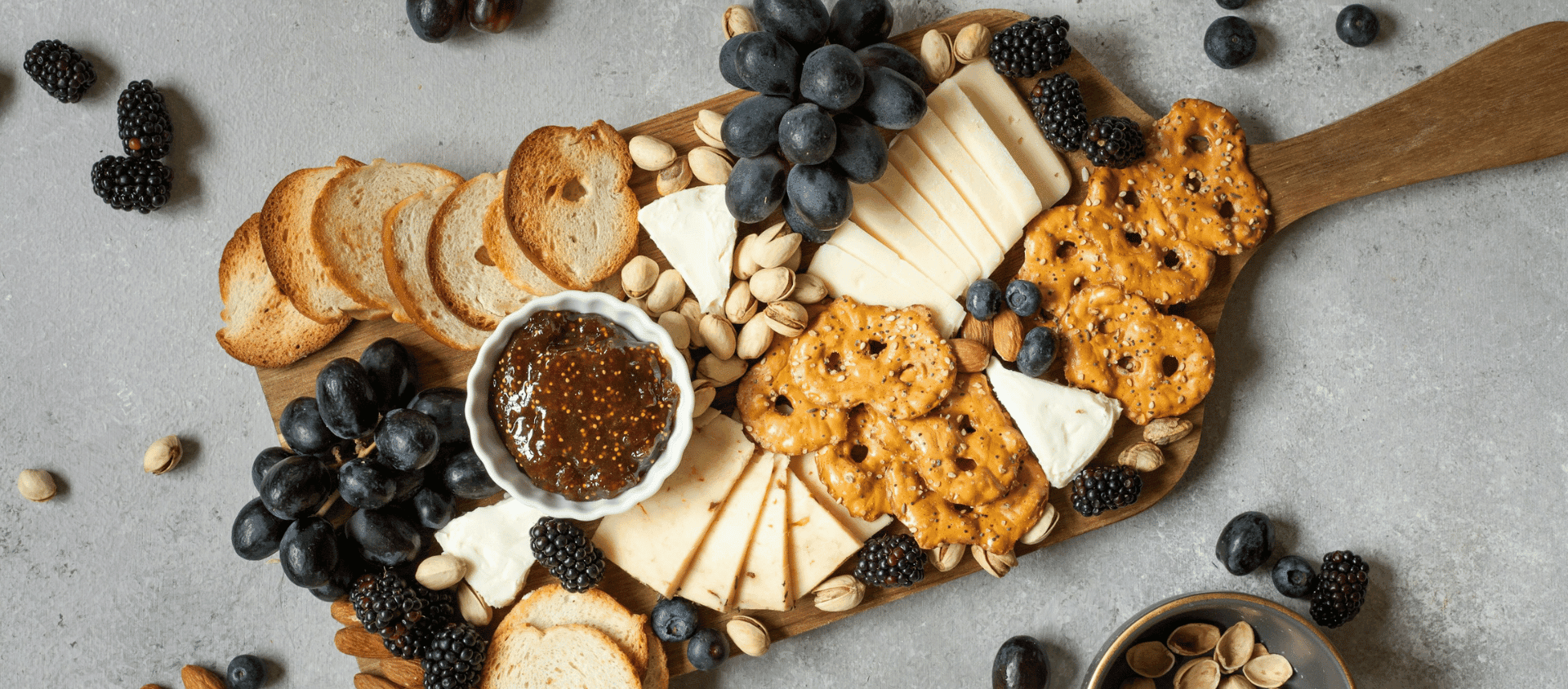 Charcuterie board with meats, cheeses, crackers, fruit, and spreads.