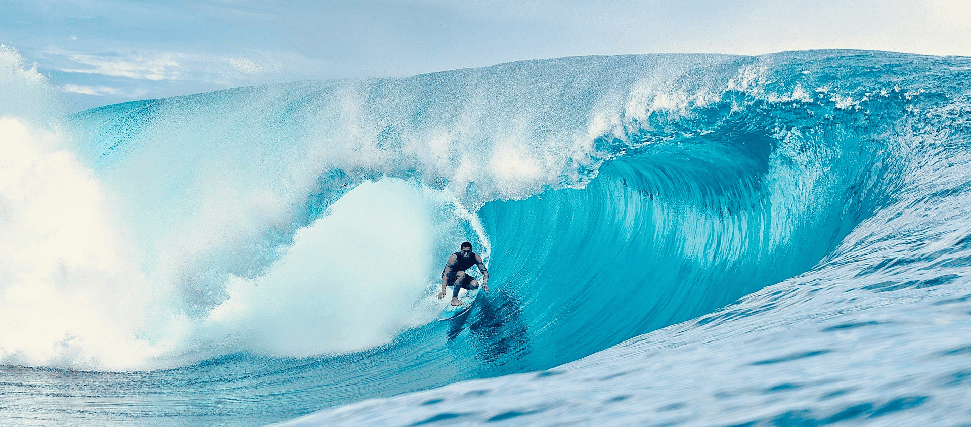 Surfer riding a barreling wave at Tahiti's famous surf break.