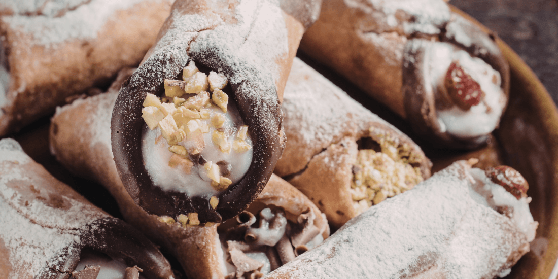 Close-up of cannoli filled with cream and dusted with powdered sugar.